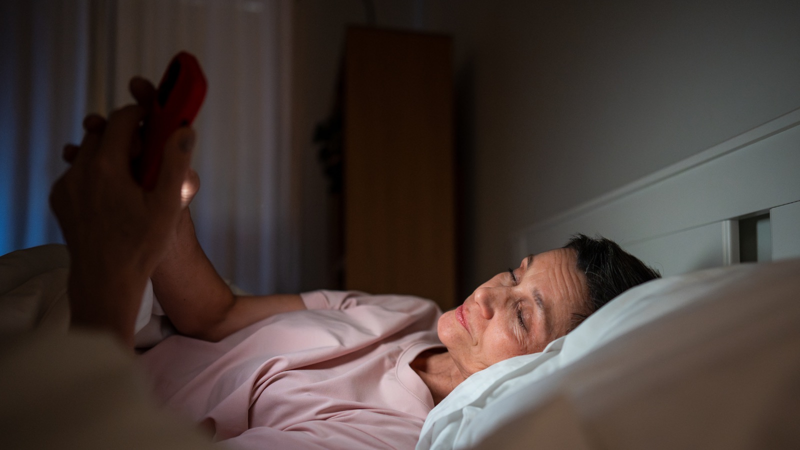 A woman using her phone in bed as part of a familiar evening routine